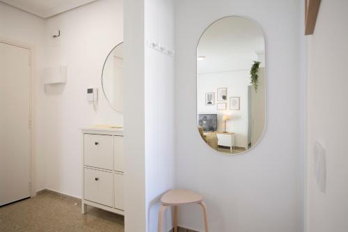 a white bathroom with a mirror and a stool at SingularStays Campanar in Valencia