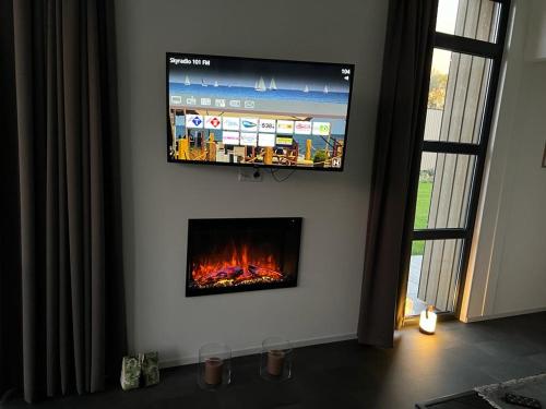 a flat screen tv hanging on a wall with a fireplace at Enkhuizer Strand Chalet WellenZeit Haus Nr 260 in Enkhuizen
