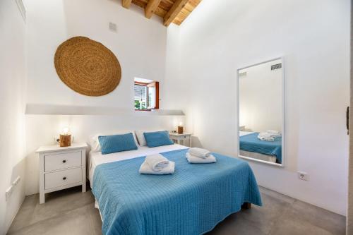 een slaapkamer met een bed met blauwe lakens en een spiegel bij Can Xumeu Ferrer in La Mola