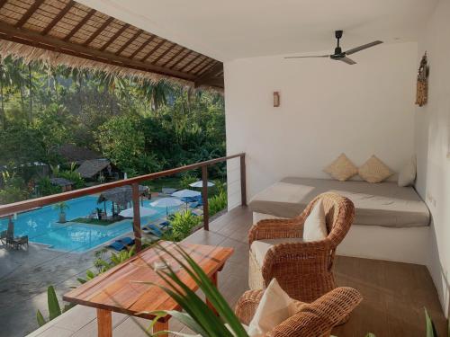 a room with a balcony with a bed and chairs at El Nido Moringa Resort in El Nido