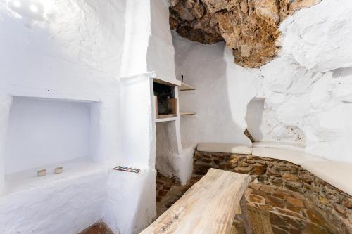 ミハスにあるLa Cuevaの白い壁と木製のベンチが備わる客室です。