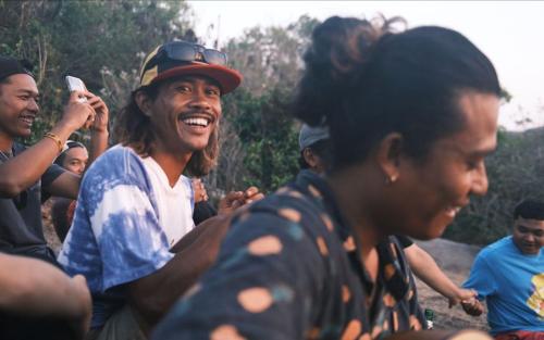 a group of people standing around a man laughing at Kala Surf Camp in Uluwatu