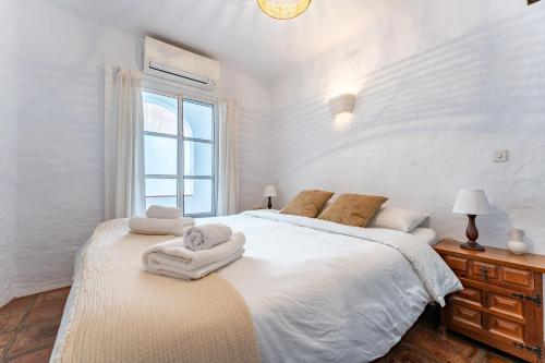 biała sypialnia z dużym łóżkiem i ręcznikami w obiekcie La Cueva w mieście Mijas