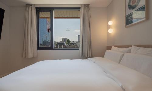 um quarto com uma grande cama branca e uma janela em Annk Hotel Daejeon Daeheung em Daejeon