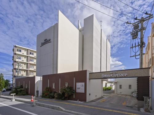 a white building with a sign on a street at Hotel Sunset Terrace in Chatan