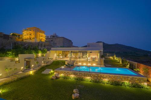 a house with a swimming pool at night at SaffronStays Villa Rohi in Udaipur