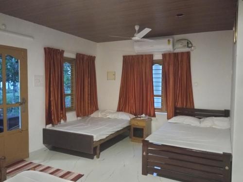 a bedroom with two beds and a window at Lake Homes in Varkala