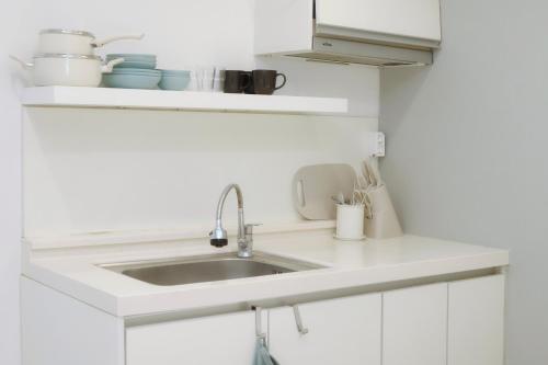 a white kitchen with a sink and cups and utensils at DADA house in Seoul