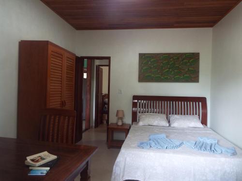 een slaapkamer met een bed en een houten tafel bij Casa Malibu in Ilha de Boipeba