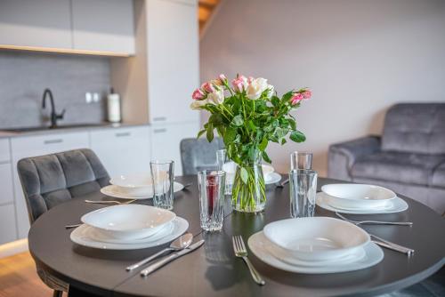a dining room table with plates and a vase of flowers at Widok 3B/6 in Piechowice