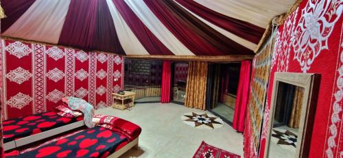 una sala de circo con una tienda roja y blanca en Bedouin Tours Camp en Wadi Rum