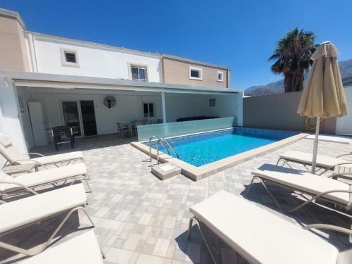 a swimming pool with lounge chairs and a house at Villa Oniro- Less than 5-Min Walk to Kalivaki Beach in Georgioupolis