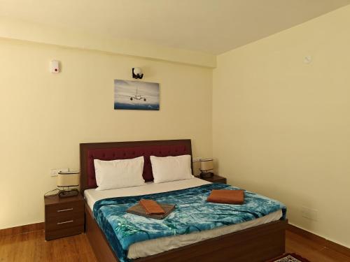 a bedroom with a bed with two boxes on it at Alooma House in Vashisht