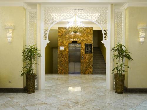 a lobby with a door with a chandelier and two plants at Al Anvar Halal Hotel by HotelPro group in Tashkent