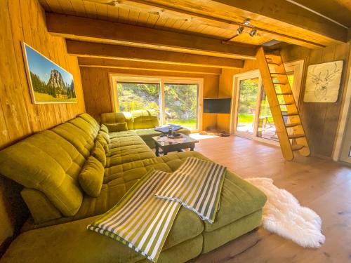 a living room with a green couch and a ladder at Chalet Wildalpen (in Ruhelage & mit Wellness) in Wildalpen