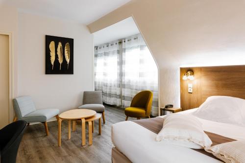 um quarto de hotel com uma cama, uma mesa e cadeiras em Logis Hotel Le Relais De La Poste Restaurant Le Fil du Temps em Thury-Harcourt