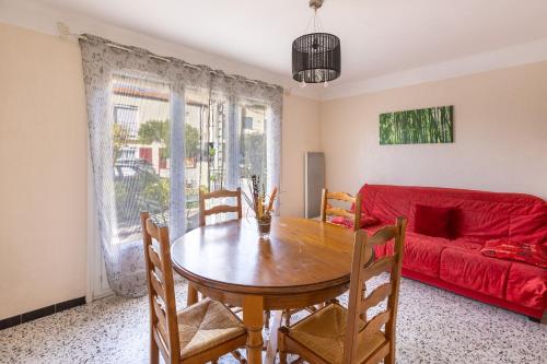 un salon avec une table et un canapé rouge dans l'établissement Pamplemousse - Appt à 10min d'Argelès-Sur-Mer, à Saint-André