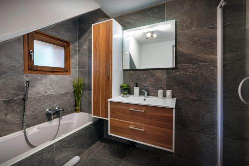 a bathroom with a sink and a bath tub and a mirror at Chalet Paravis - OVO Network in La Clusaz