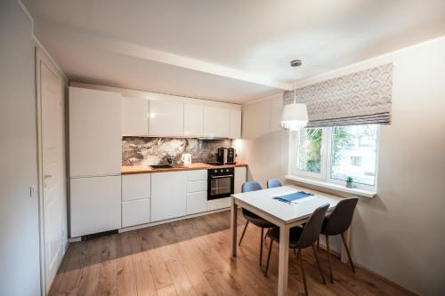 a kitchen with white cabinets and a table and chairs at Cabin Guesthouse in P&auml;rnu