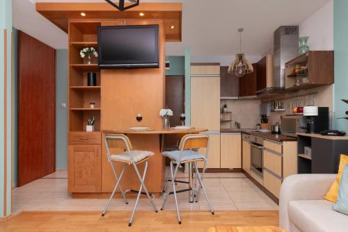 a kitchen with a table and chairs and a tv on a wall at Subtle and Cosy Studio with Furnished Balcony in Gdańsk by Noclegi Renters in Gdańsk