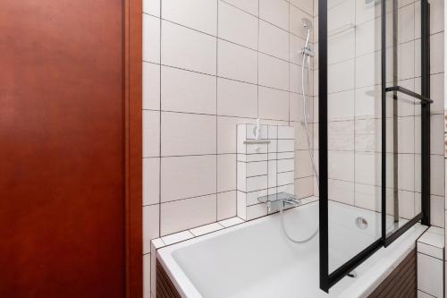 a bathroom with a bath tub and a shower at Subtle and Cosy Studio with Furnished Balcony in Gdańsk by Noclegi Renters in Gdańsk