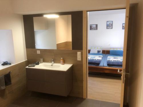 łazienka z umywalką, lustrem i łóżkiem w obiekcie B&B Alpina w mieście Le Prese