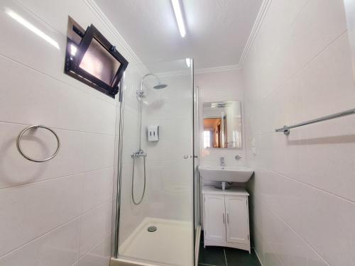 La salle de bains blanche est pourvue d'une douche et d'un lavabo. dans l'établissement Casa en centro de Santana con vista al mar y la montaña, à Santana