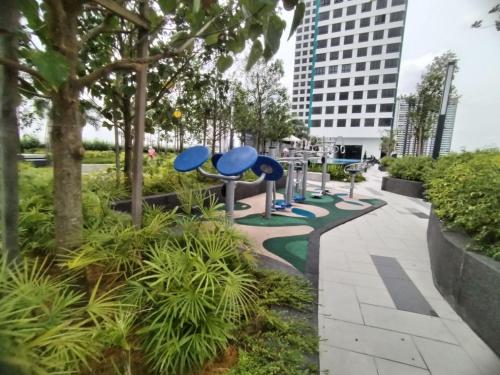 a park with blue benches and trees and a building at Japandi Family Play Suite with Slide Bunk Bed in Kajang