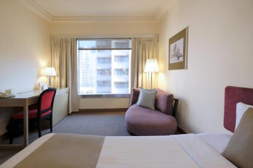 a hotel room with a bed and a desk and a window at Prudential Hotel in Hong Kong