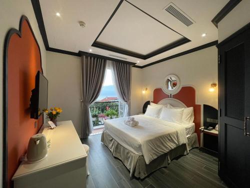 a hotel room with a bed and a window at Le Bonheur Hotel in Phú Quốc