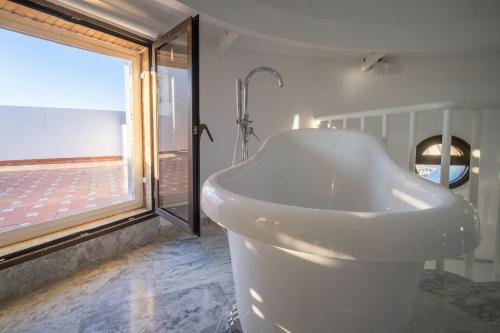 uma banheira branca na casa de banho com uma janela em Conjunto de APARTAMENTOS ANTIGUO PALACIO HOTEL PARIS em Huelva