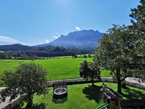 a bridge over a green field with mountains in the background at Ferienwohnung Kramerhof in Ebbs