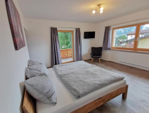 1 dormitorio con 1 cama, 1 silla y 1 ventana en Ferienwohnung Kramerhof, en Ebbs