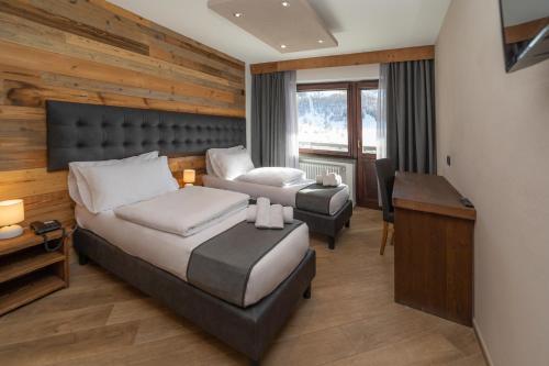 a bedroom with a bed and a couch and a desk at Hotel Gran Roc in Sestriere
