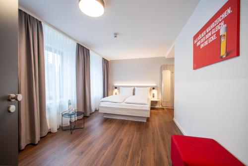 a bedroom with a white bed and a red couch at Eden Hotel Früh am Dom in Cologne