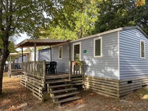 a blue tiny house with a porch and a deck at Camping du Lac in Marcillac-la-Croisille