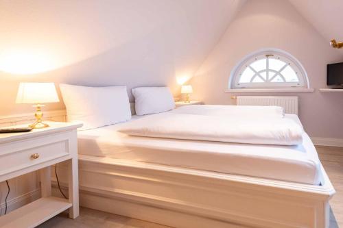 un letto bianco in una stanza con finestra di LH Isernhagenhof, App 3 a Wenningstedt