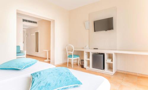 1 dormitorio con 1 cama y TV en la pared en Hotel Cala Dor - Adults Only, en Cala d´Or