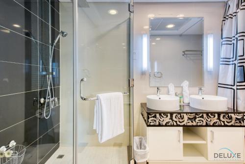 a bathroom with two sinks and a glass shower at Calm 3BR in The Signature Downtown by Deluxe Holiday Homes in Dubai