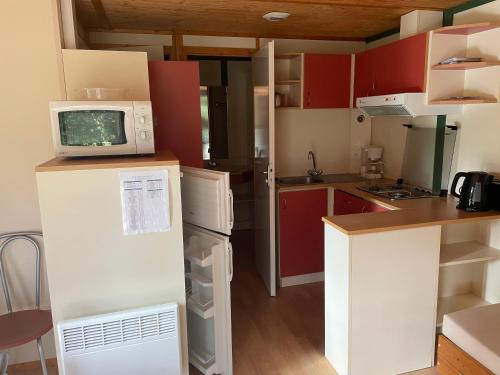 a kitchen with a microwave on top of a refrigerator at Camping du Lac in Marcillac-la-Croisille