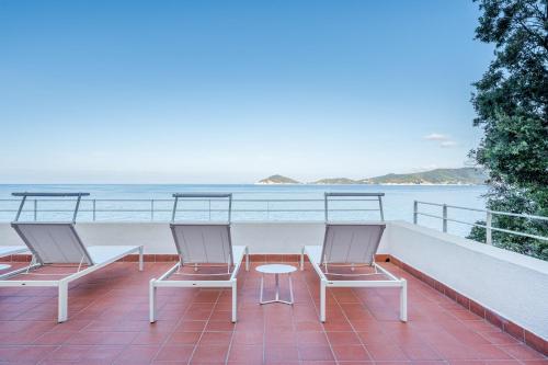 three chairs and a table on a balcony overlooking the ocean at Villa Escalina with private beach and A/C in Marciana Marina