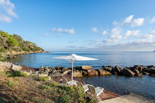 un gruppo di sedie e un ombrellone su una spiaggia di Villa Escalina with private beach and A/C a Marciana Marina