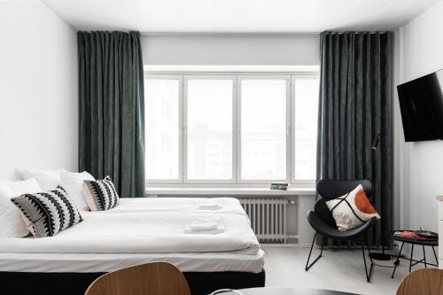 a bedroom with a bed and a chair and a window at Prime Apartments Pori Central in Pori