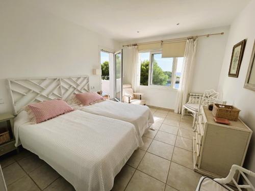 um quarto com uma grande cama branca com almofadas cor-de-rosa em Villa Sa Gavina, Caló des Llamp em Porto Petro
