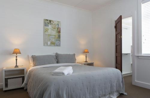 ニュープリマスにあるMichelia Figo Cottageの白いベッドルーム(大型ベッド1台、ナイトスタンド2台付)
