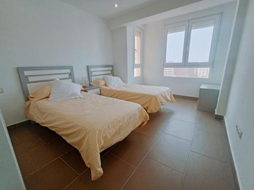 two beds in a room with two windows at Caminos del Mediterráneo in Castellón de la Plana