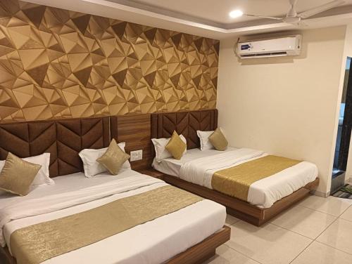 a bedroom with two beds and a wall at Hotel Lake View AC room in Vadodara