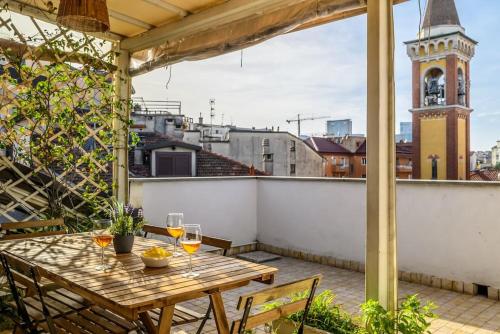 un tavolo in legno su un balcone con torre dell'orologio. di Buenos Aires' Nest - 10 minutes from Duomo with terrace a Milano