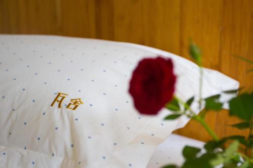 a red rose sitting on top of a white pillow at Xi'an Travelling with Hotel South Gate in Xi'an