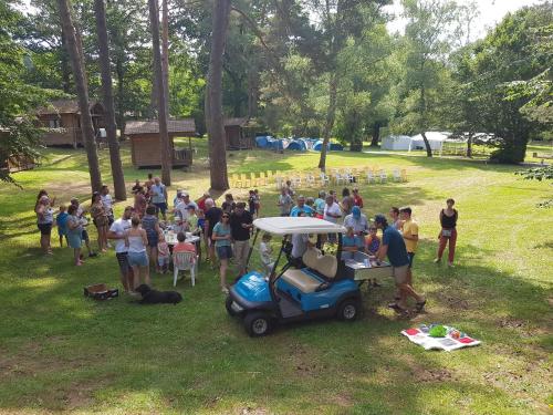 a crowd of people in a park with a golf cart at Camping du Lac in Marcillac-la-Croisille